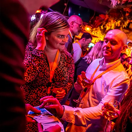Gasten kijken vol spanning naar een kaarttruc van goochelaar Jan Smulders tijdens een bedrijfsevenement bij de Holy Moly Club.