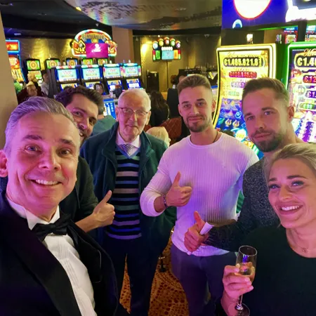Een enthousiaste groep gasten op de foto met goochelaar Jan Smulders na een geslaagde table magic act bij Holland Casino.