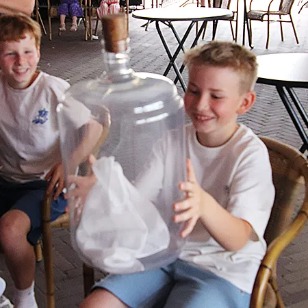 Interactieve goochelshow: een enthousiaste jongen houdt het magisch dansende doekje in de fles vast in Herveld.